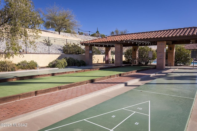 view of home's community with fence and shuffleboard