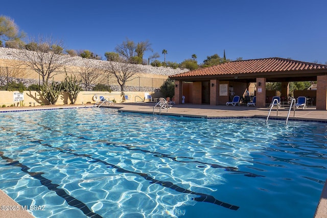 community pool with a patio area and fence