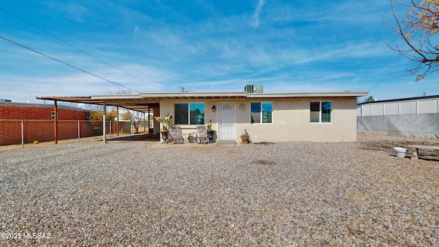 view of front of property with fence, a carport, and stucco siding