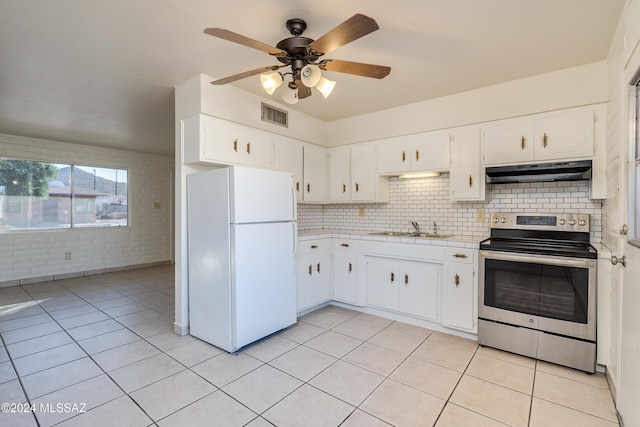 kitchen with a sink, visible vents, light countertops, freestanding refrigerator, and stainless steel range with electric stovetop