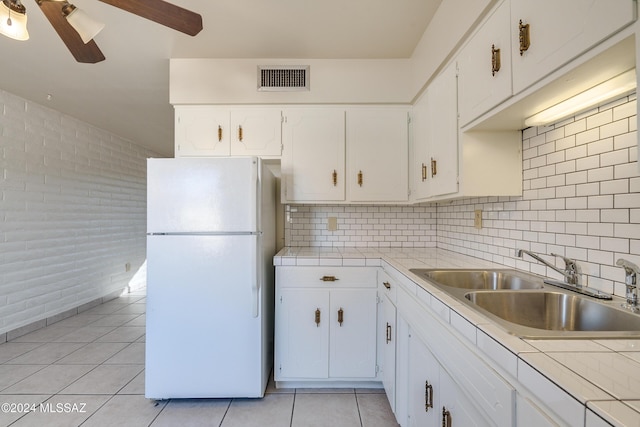 kitchen with white cabinetry, light countertops, and freestanding refrigerator