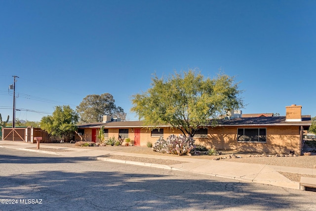 single story home featuring a gate, fence, and a chimney