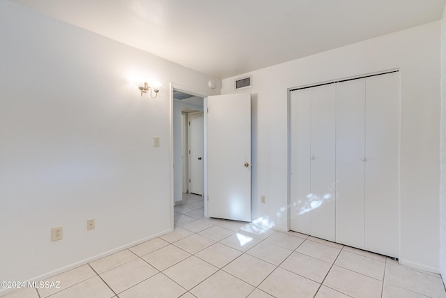 unfurnished bedroom featuring a closet, visible vents, baseboards, and light tile patterned floors