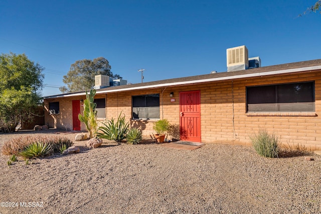 ranch-style house featuring cooling unit and brick siding