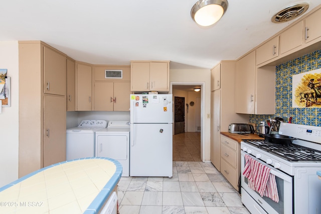 kitchen featuring white appliances, visible vents, washing machine and clothes dryer, and cream cabinetry