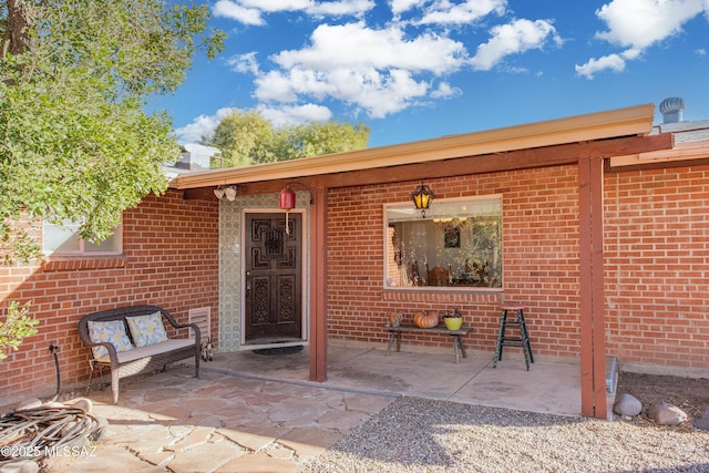 entrance to property with brick siding and a patio area