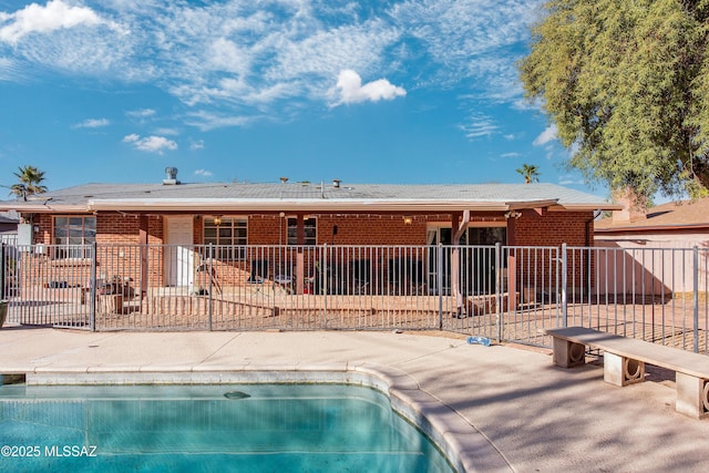 rear view of house featuring a fenced in pool, a patio area, brick siding, and fence