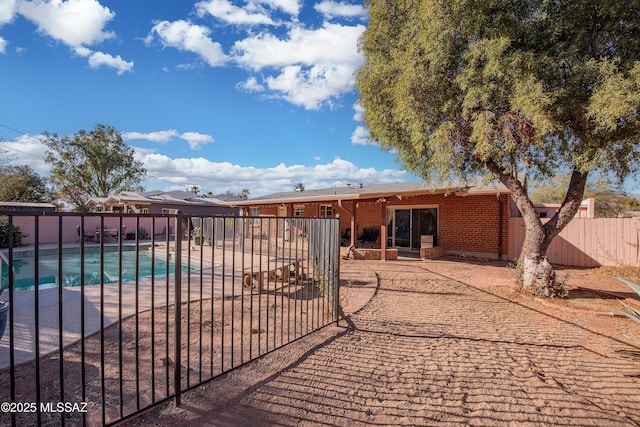 rear view of house with brick siding, a patio area, fence, and a fenced in pool