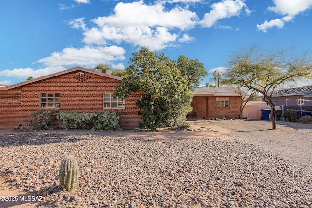 exterior space featuring brick siding and fence