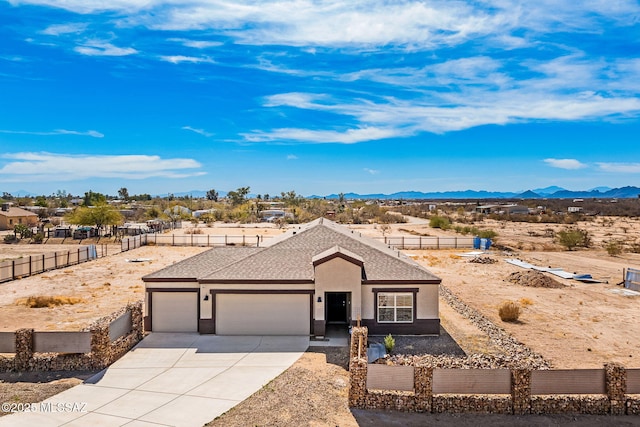 ranch-style house with an attached garage, a mountain view, a shingled roof, concrete driveway, and stucco siding