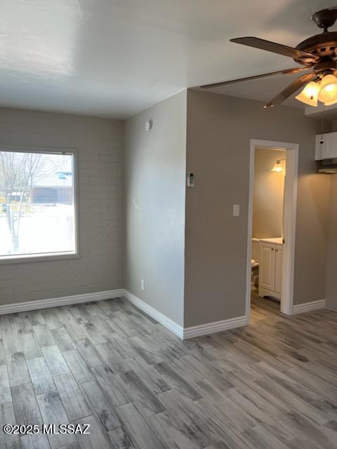 spare room featuring baseboards, wood finished floors, and a ceiling fan
