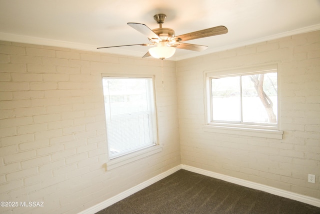 spare room featuring baseboards, dark colored carpet, brick wall, and ceiling fan