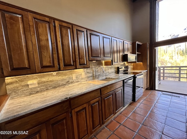 kitchen featuring stainless steel microwave, backsplash, range with electric stovetop, plenty of natural light, and a sink