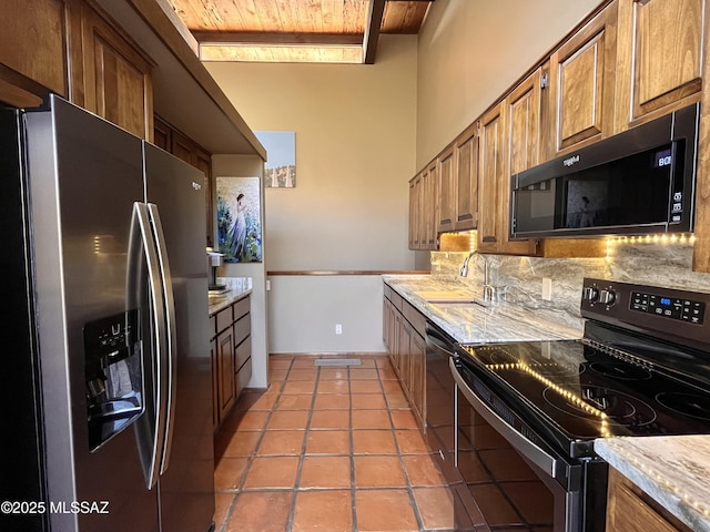 kitchen featuring electric range, stainless steel refrigerator with ice dispenser, a sink, backsplash, and black microwave