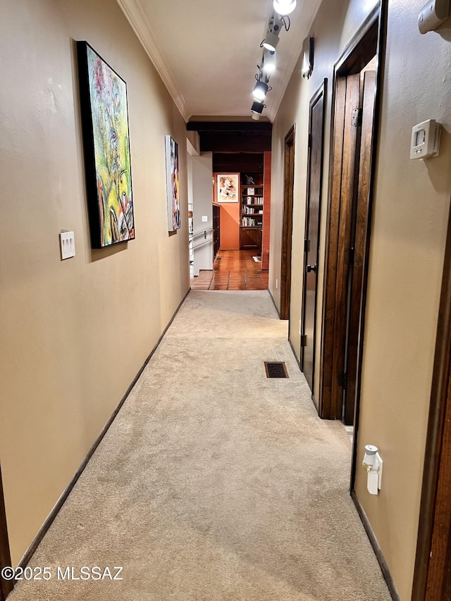 hall with track lighting, visible vents, crown molding, baseboards, and carpet flooring