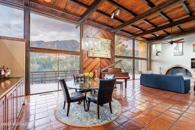 dining area featuring expansive windows, beam ceiling, wooden ceiling, a fireplace, and a mountain view