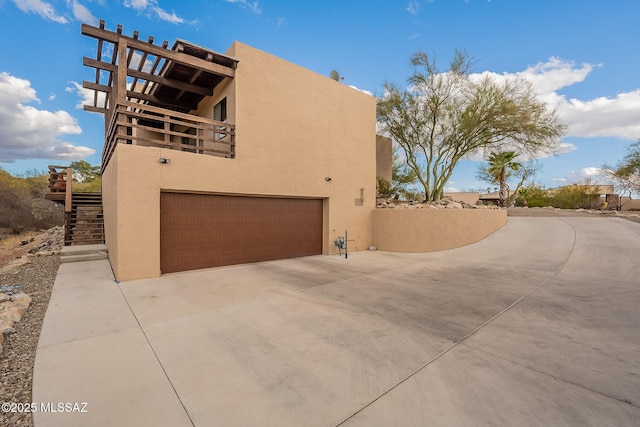 view of side of home with stucco siding, stairs, and a garage