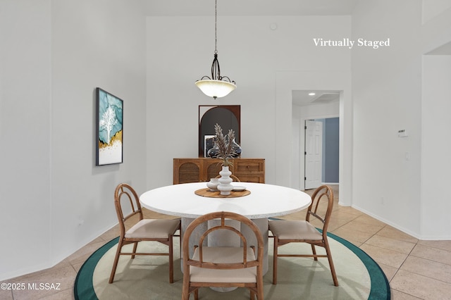 dining area with light tile patterned flooring, a towering ceiling, and baseboards