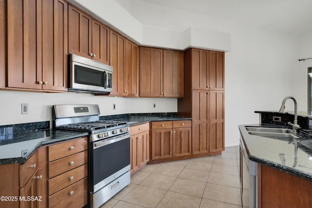 kitchen with appliances with stainless steel finishes, dark stone counters, brown cabinetry, and a sink