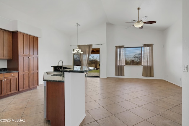 kitchen with brown cabinetry, hanging light fixtures, light tile patterned flooring, a sink, and ceiling fan with notable chandelier