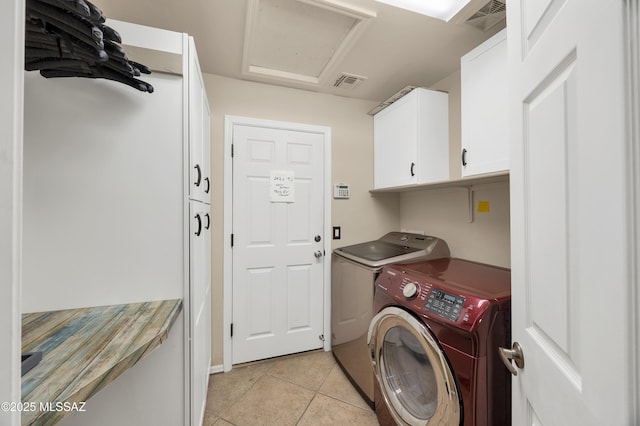 washroom with light tile patterned floors, cabinet space, washing machine and clothes dryer, and visible vents