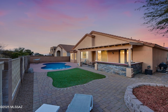 rear view of property with a fenced in pool, a fenced backyard, a patio, and stucco siding