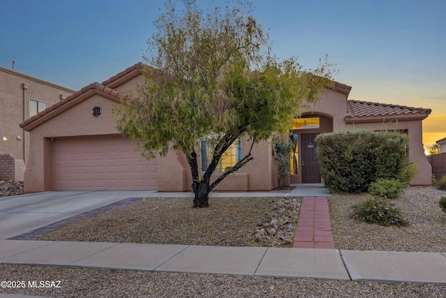 view of front facade with a garage, concrete driveway, and stucco siding