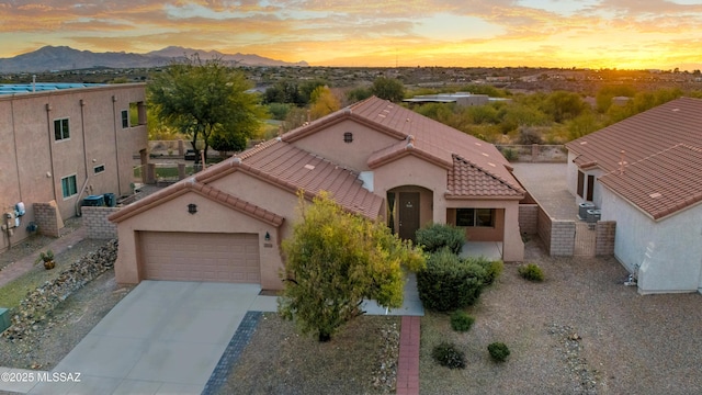 view of front of home with driveway, a tile roof, an attached garage, a mountain view, and stucco siding