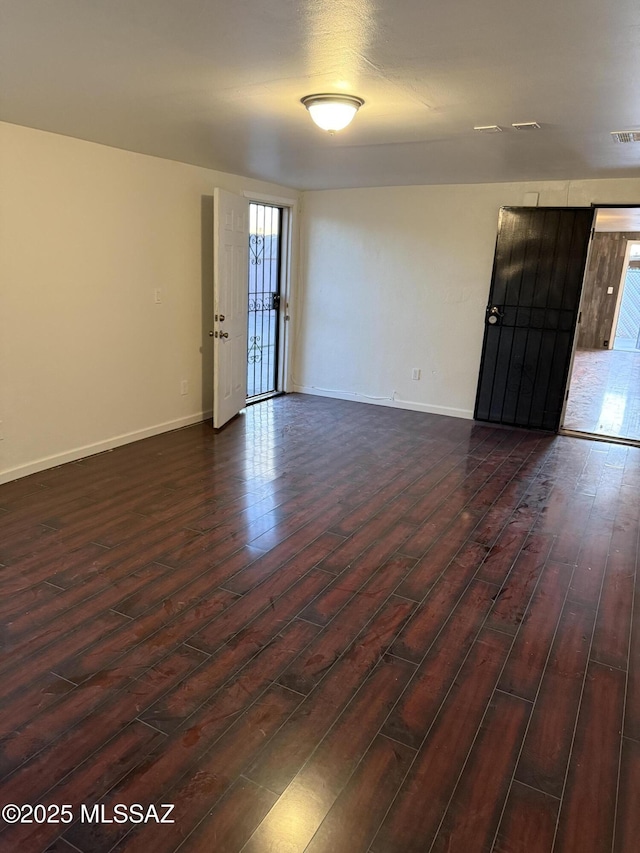 empty room featuring baseboards and dark wood-type flooring