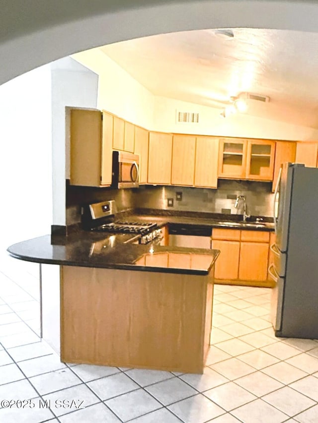 kitchen featuring stainless steel appliances, visible vents, light tile patterned flooring, a sink, and a peninsula