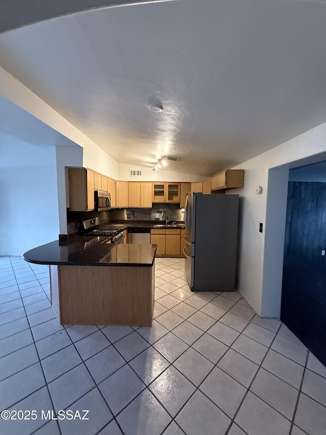 kitchen featuring stainless steel appliances, dark countertops, light tile patterned flooring, and a peninsula