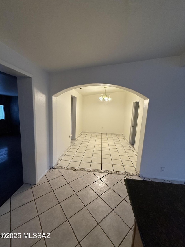 empty room featuring light tile patterned floors and arched walkways