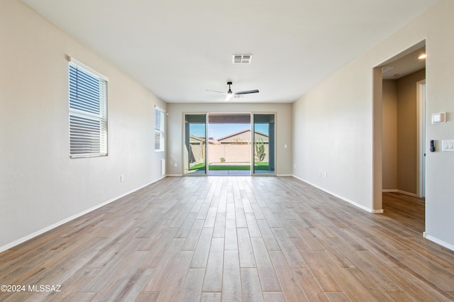 unfurnished room featuring baseboards, light wood-type flooring, visible vents, and a ceiling fan