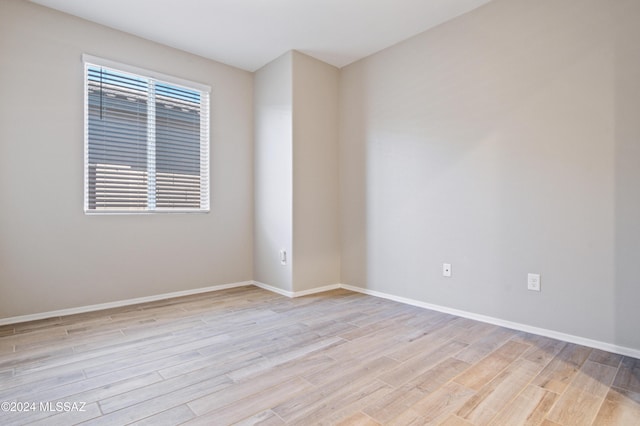 spare room featuring light wood-style floors, a wealth of natural light, and baseboards