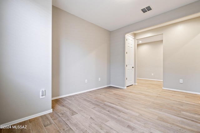 empty room with light wood-type flooring, visible vents, and baseboards