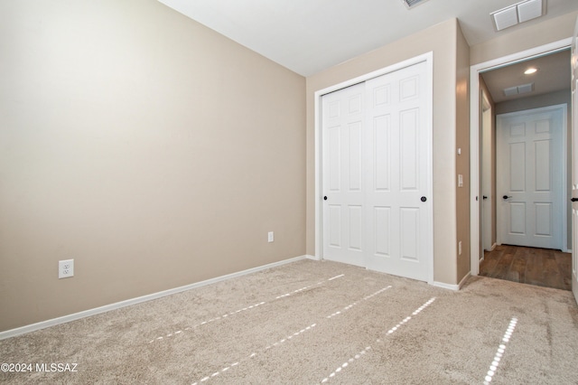 unfurnished bedroom featuring carpet floors, a closet, visible vents, and baseboards