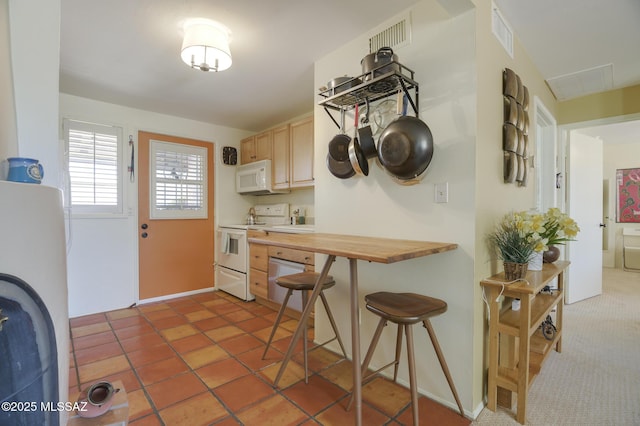 kitchen featuring white appliances, light brown cabinets, visible vents, butcher block countertops, and a kitchen breakfast bar