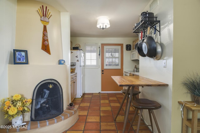 interior space featuring tile patterned flooring, white appliances, a kitchen bar, and butcher block counters