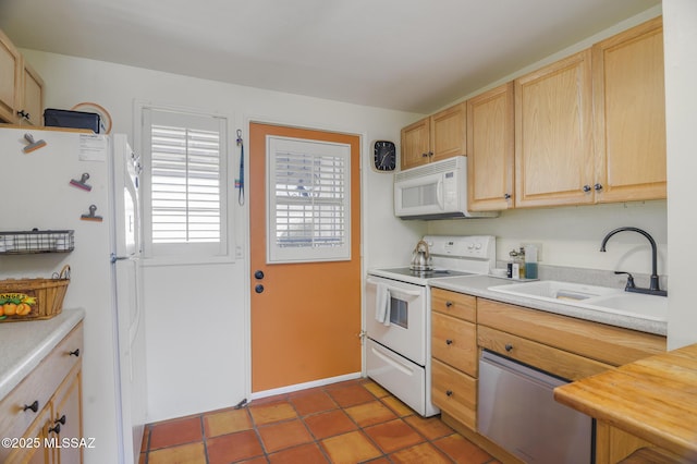 kitchen with tile patterned floors, light brown cabinetry, a sink, white appliances, and light countertops