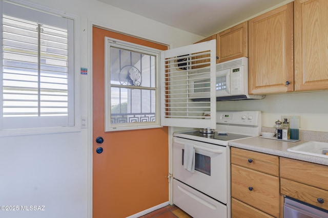 kitchen featuring light brown cabinets, white appliances, and light countertops