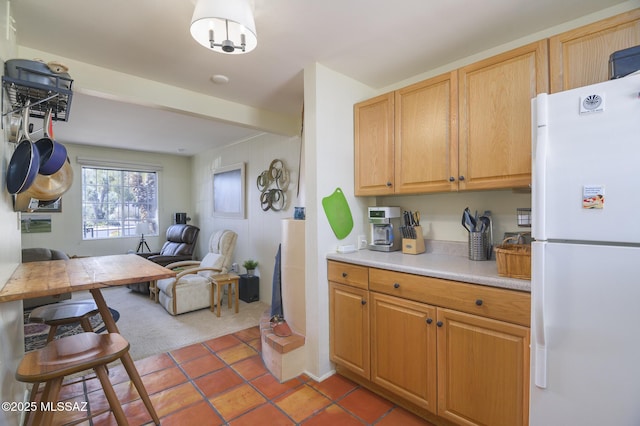 kitchen with open floor plan, light countertops, beam ceiling, carpet flooring, and freestanding refrigerator