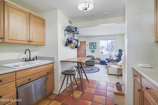 kitchen with light brown cabinetry, a sink, light countertops, tile patterned floors, and open floor plan