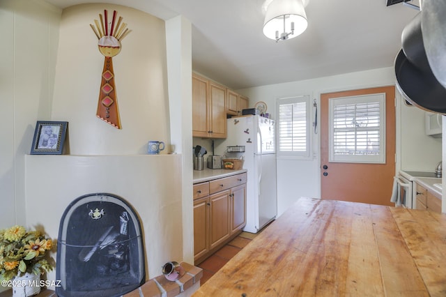 kitchen featuring white appliances, light brown cabinetry, and wood counters