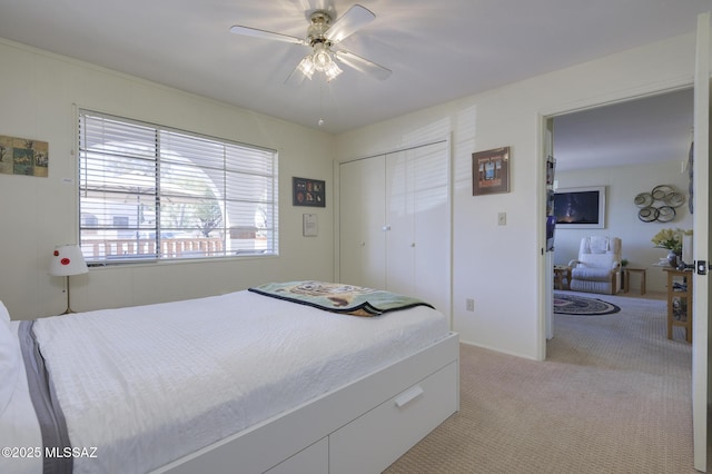 bedroom featuring light carpet, ceiling fan, and a closet