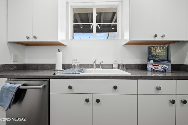 kitchen with dark countertops, white cabinetry, and dishwasher