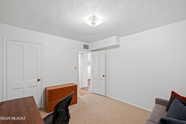 office space featuring baseboards, visible vents, light carpet, and a textured ceiling