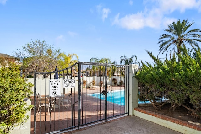 view of gate featuring fence and a fenced in pool