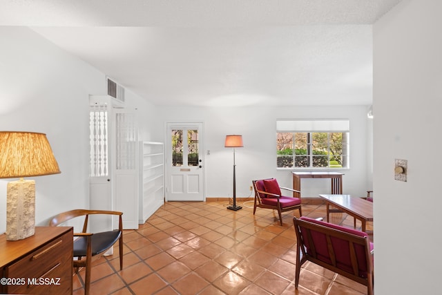 living area featuring tile patterned flooring, visible vents, and baseboards