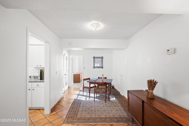 dining space with a textured ceiling, baseboards, and light tile patterned floors