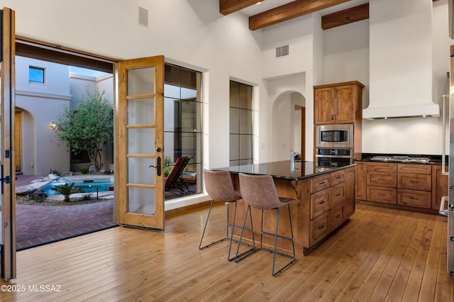 kitchen featuring arched walkways, appliances with stainless steel finishes, a kitchen island, and visible vents